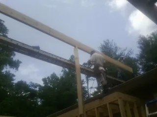 Carpenter setting a ridge beam over a new addition frame — Ice Dam Removal by Roofing Brothers in Pitcher