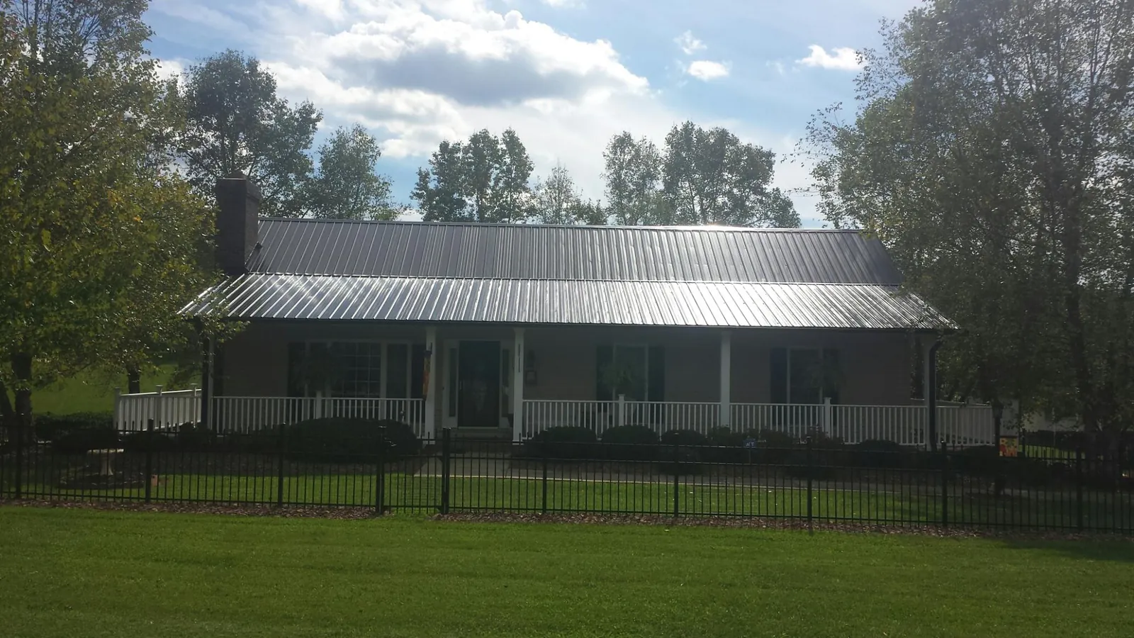 Gray metal roof on a brick ranch with a full width front porch — Gutter Guard Installation work by our crew in Pitcher