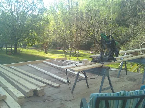 Miter saw and framing lumber on a deck under construction in Pitcher