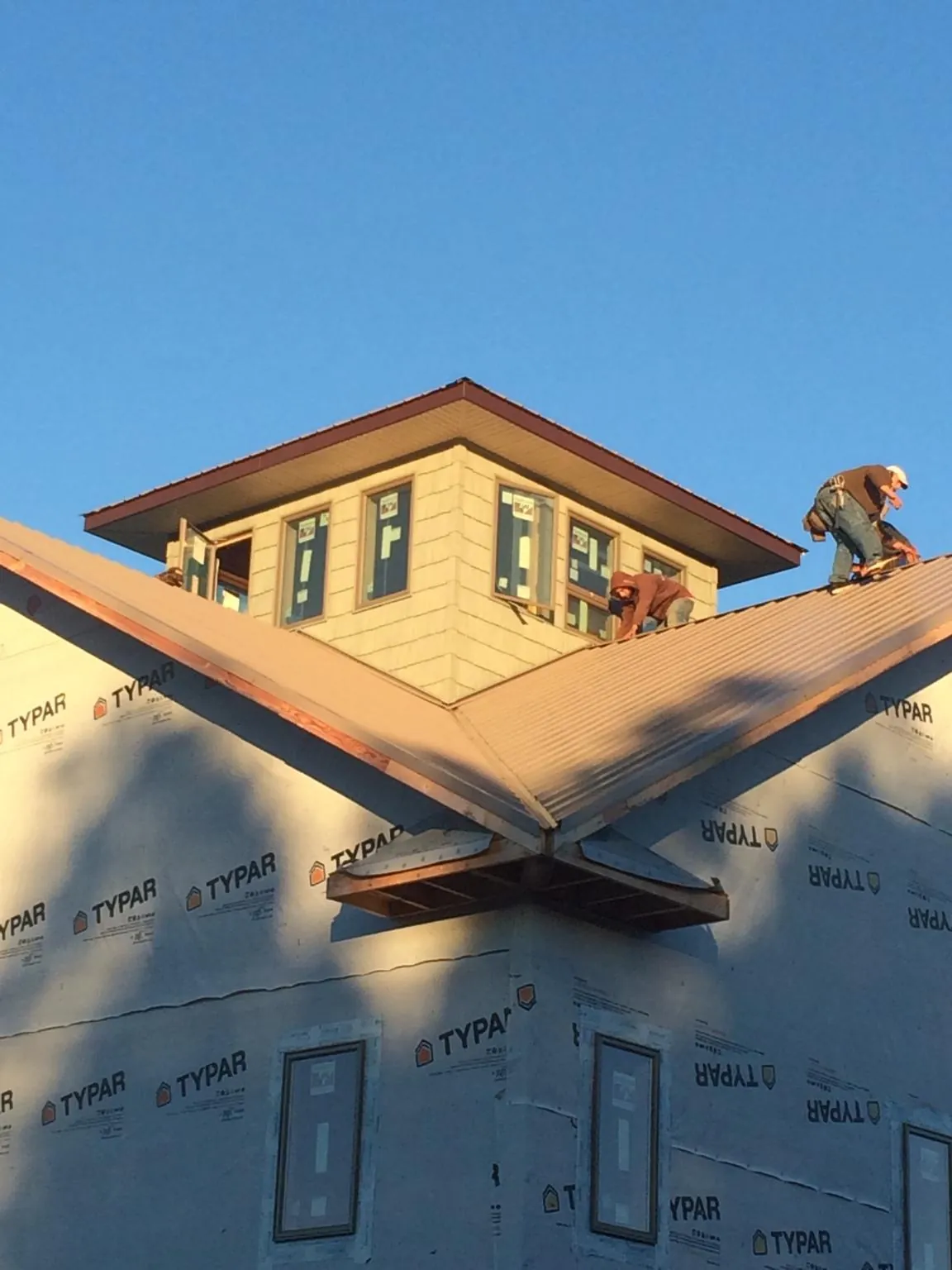 Roofers working around a rooftop cupola on a new metal roof at sunset — Roof Waterproofing in Pitcher by Roofing Brothers